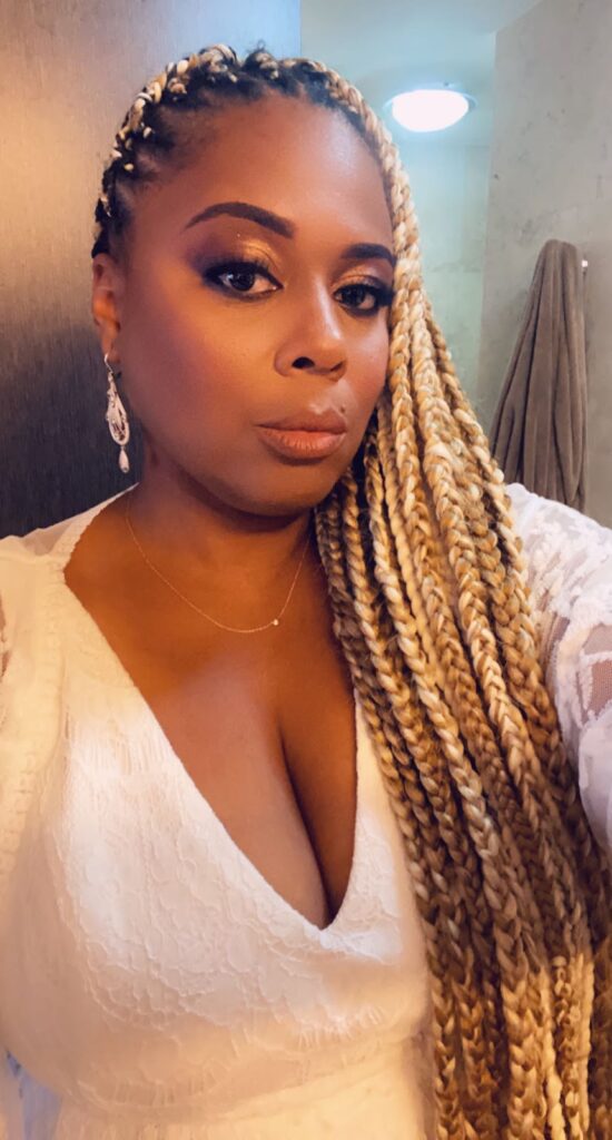 African American female in white lace jumpsuit with blonde braids post surprise Aruba engagement.