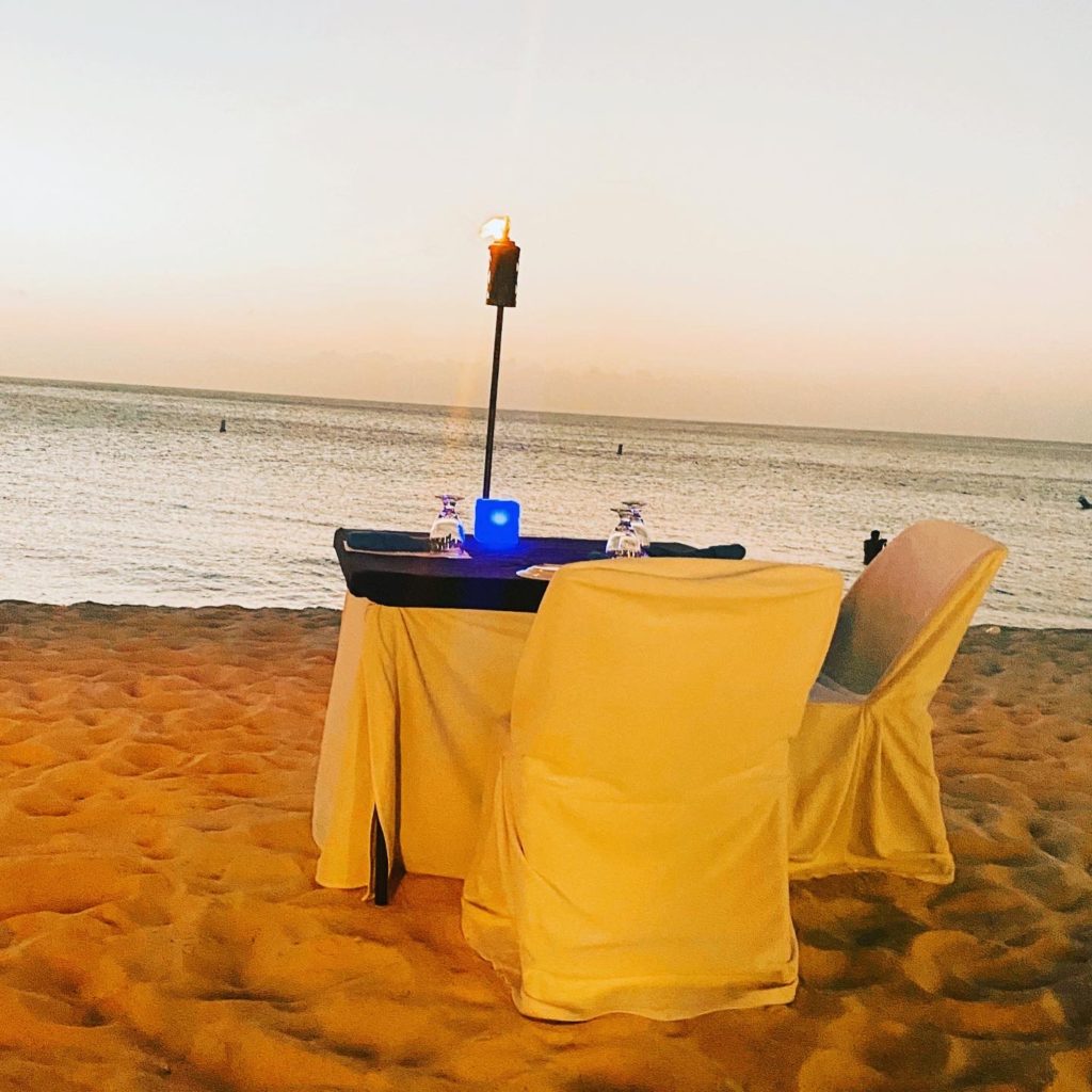 Romantic dinner directly on the sand of Eagle Beach overlooking the perfect sunset at Passions on the Beach restaurant in Aruba.